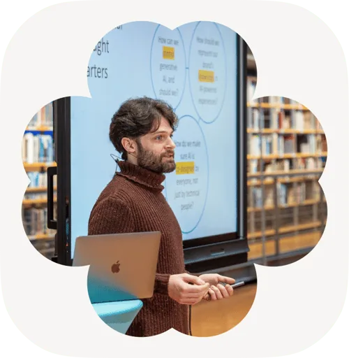 A facilitator presenting AI workshop slides beside a laptop in a library setting